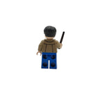 LEGO figure with a brown jacket and blue pants holding a black object on a white background