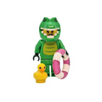 Toy figure of a green creature with a pink life preserver and yellow duck on a white background