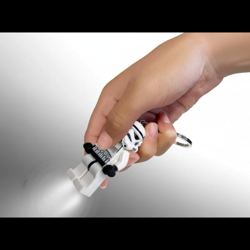 Hand holding a white and black keychain light with a gray background