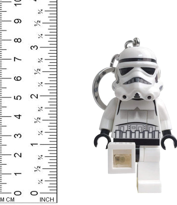 LEGO Stormtrooper keychain with a small square object next to a ruler for scale on a white background